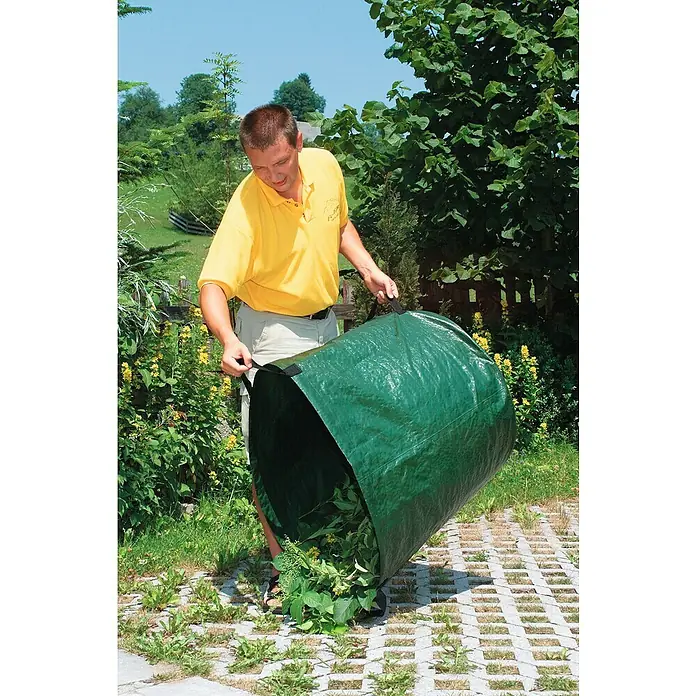 Windhager Gartenabfallsack - 80 l - Mann, der einen grünen Gartensack mit Griffen hält, gefüllt mit Gartenabfällen, auf einem Rasen mit Steinen.