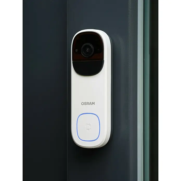 Osram Smart+ Türklingel mit Kamera - Weiß - Intelligente OSRAM-Türklingel mit Kamera und Klingelknopf, montiert an einer dunklen Wand, für verbesserte Haussicherheit.