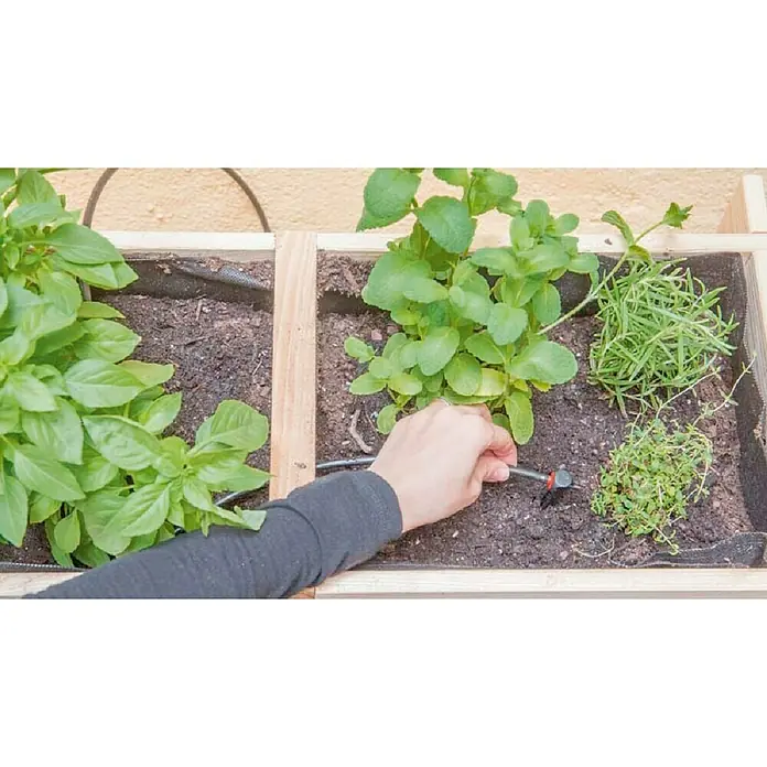 Set de iniciación Multigoteo - Apto para: Riego en línea - Un jardín de hierbas de madera con riego por goteo integrado que se está plantando, asegurando un riego óptimo para las hierbas.