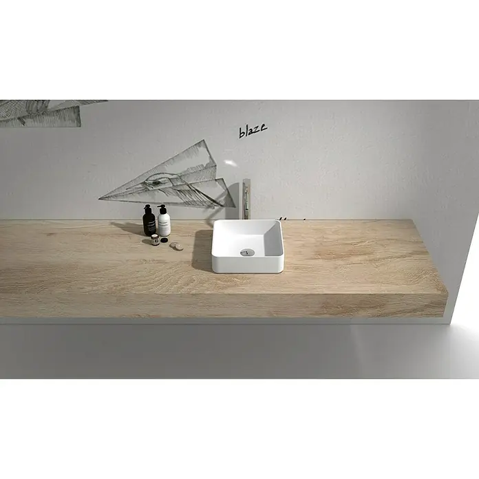 Camargue Lavabo Molí - 38 x 38 cm, Con esmalte antibacteriano, Sin desbordamiento, Blanco - Un lavabo cuadrado sobre una encimera de madera clara, al lado de dispensadores de jabón, frente a una pared con dibujos.