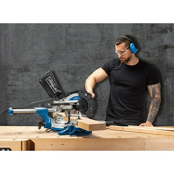 Scheppach Tronzadora HM 254 - 2.000 W, Diámetro hoja de sierra: 255 mm, 4.500 r.p.m. - Un hombre utiliza una sierra ingletadora Scheppach, con gafas y protectores auditivos para un uso seguro.