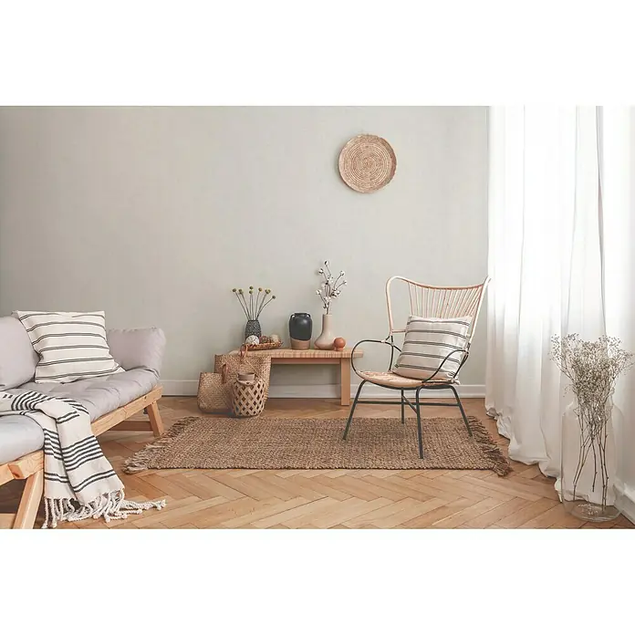 A.S. Création New Walls VliestapeteWeiß/Creme, Uni, 10,05 x 0,53 m - Ein stilvolles Interieur mit einem Sessel, Sofa und einem Teppich, die eine gemütliche Atmosphäre schaffen.