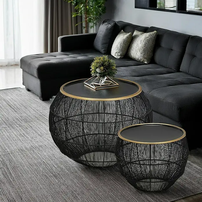Beistelltisch Mika - 2 -tlg., Schwarz, Metall - Zwei dekorative, schwarze Draht-Couchtische mit goldfarbenen Akzenten und schwarzen Tischplatten stehen vor einem grauen Sofa.