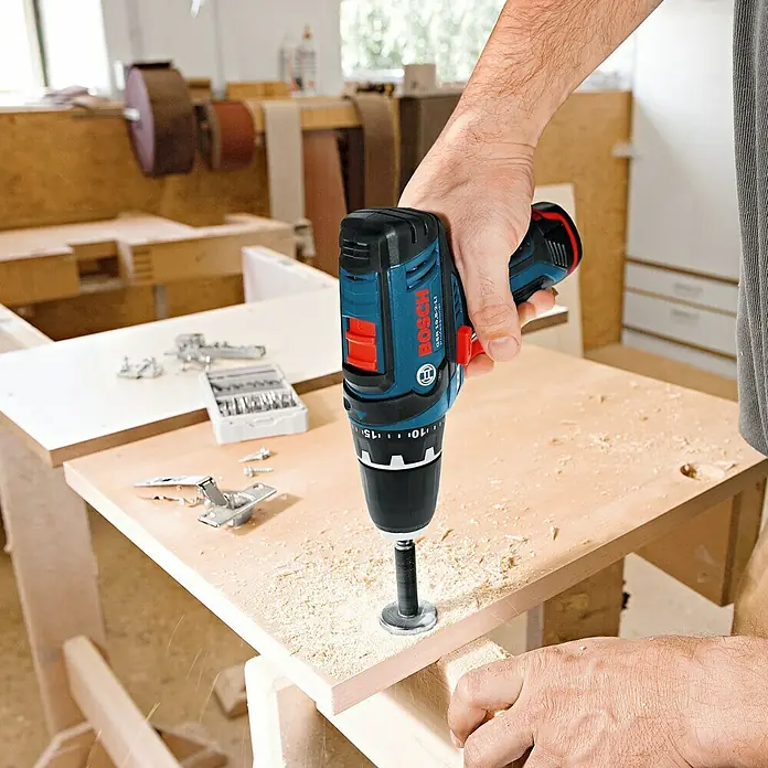 Bosch Professional Akku-Bohrschrauber GSR 12V-15 - 12 V, Ohne Akku, 30 Nm - Nahaufnahme eines Bosch GSR 12V-15 FC Professional Akku-Bohrschraubers beim Bohren in ein Holzbrett in einer Werkstatt.