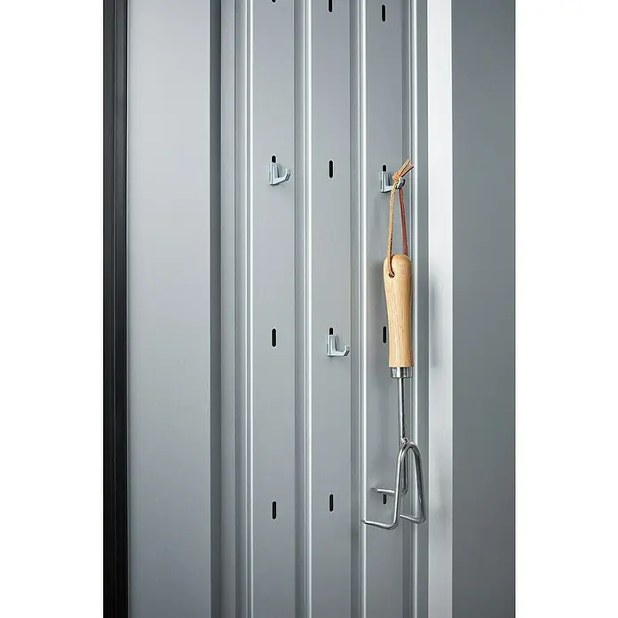 Biohort Romeo Geräteschrank - Außenmaß inkl. Dachüberstand (B x T): 132 x 57 cm, Stahl, Quarzgrau-Metallic - Ein Gartenwerkzeug mit Holzgriff hängt an einem grauen, vertikalen Hängesystem mit Haken. Praktische Aufbewahrung für Gartengeräte.