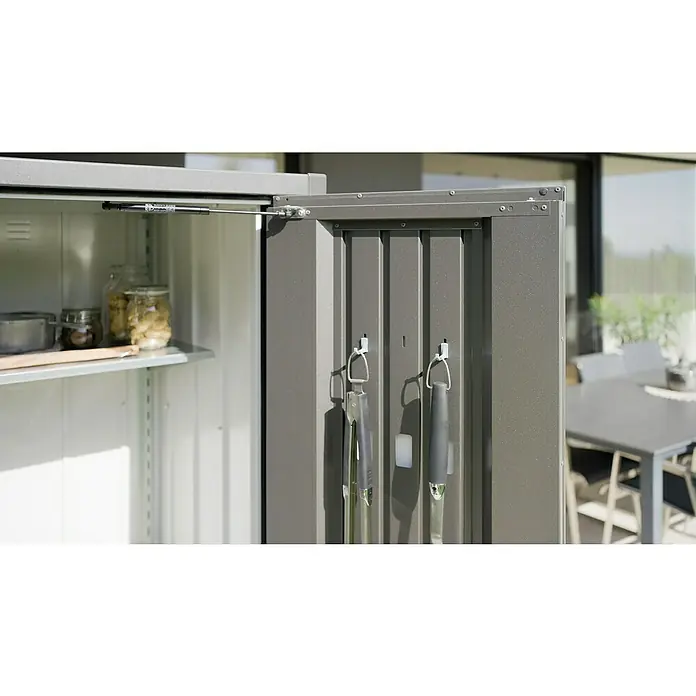 Biohort Romeo Geräteschrank - Außenmaß inkl. Dachüberstand (B x T): 132 x 57 cm, Stahl, Quarzgrau-Metallic - Aufnahme eines Metallschranks im Freien mit Regalen und Werkzeugen an der Tür. Das Produkt ist ein Outdoor-Aufbewahrungsschrank.
