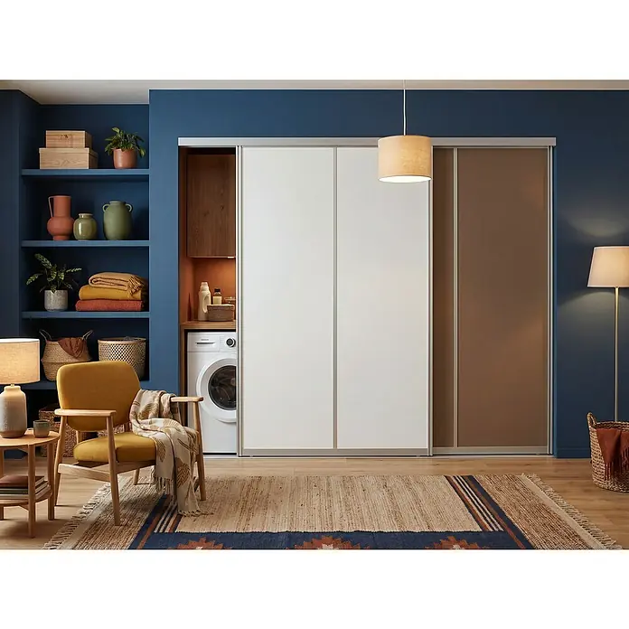 Room Plaza Easy Schiebetür-Bau-Set - Taupe/Weiß Miniperl, Farbe Beschlag: Silber - Das Bild zeigt einen modernen Wäscheschrank mit Schiebetüren in Weiß und Braun, der in ein stilvolles blaues Interieur integriert ist.