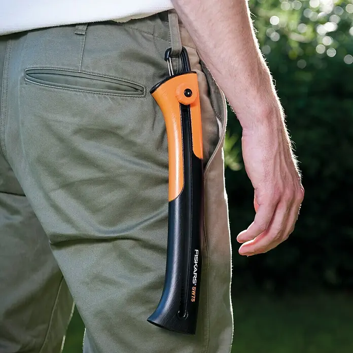 Fiskars Hand-Astsäge Xtract SW75 - Länge: 33 cm, Max. Aststärke: 220 mm, Kunststoff, Orange/Schwarz - Nahaufnahme einer Fiskars SW75 Astsäge, die an einer Hose befestigt ist. Das Sägeblatt ist sicher in der orange-schwarzen Scheide verstaut.