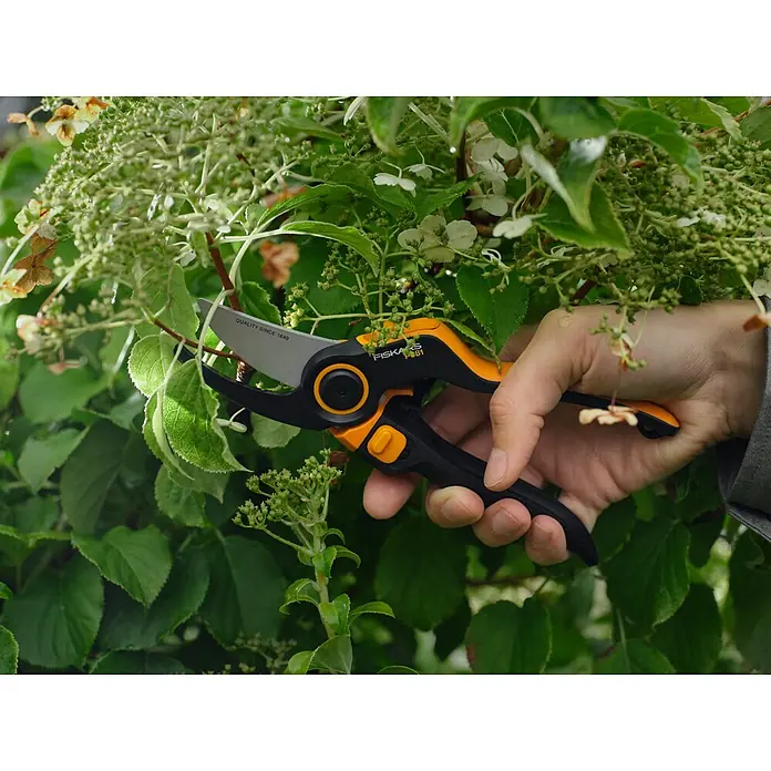 Fiskars X-series Gartenschere DualAction P981 - Bypass, Max. Aststärke: 26 mm - Nahaufnahme einer Hand, die mit einer Fiskars Gartenschere Äste schneidet.