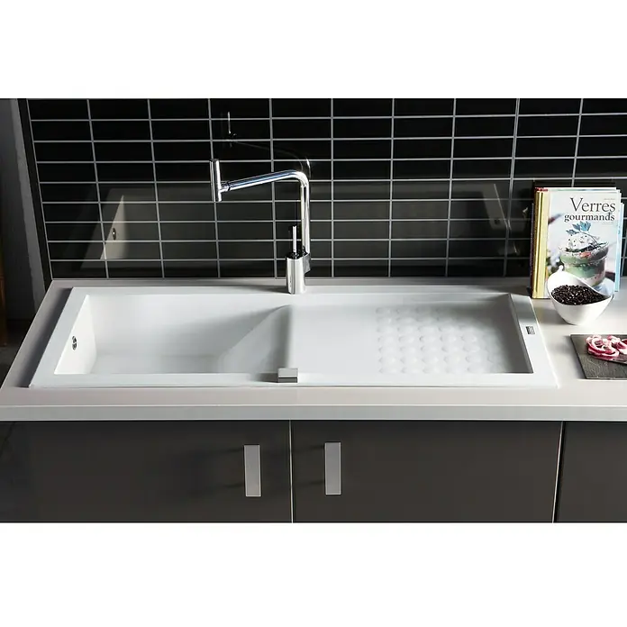 Carea Einbauspüle Vague - 118 x 50 cm, Weiß, Material Spüle: CAREAgranit® - Einbau-Küchenspüle mit Abtropffläche und schwarzer Fliesenwand im Hintergrund, sowie Armatur und Deko.