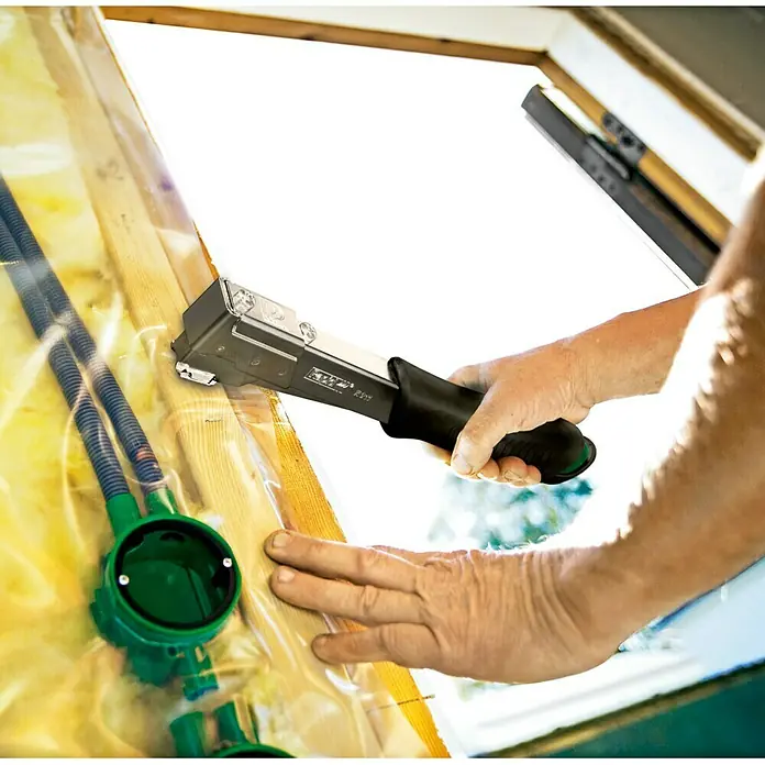 Rapid Hammertacker R311 - Klammertiefe: 6 mm - 12 mm, Geeignet für: Flachdrahtheftklammern Typ 140 (6 - 12 mm) - Eine Nahaufnahme einer Hand, die einen Rapid EN50 Handtacker hält, mit dem eine Plastikfolie an einem Fensterrahmen befestigt wird.