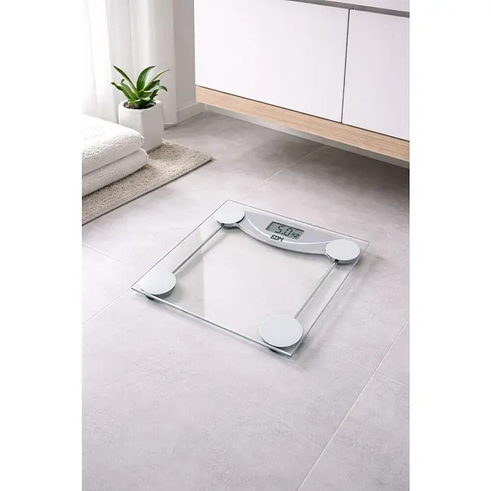 Báscula digital transparente - 30 x 30 x 3 cm, Vidrio, Transparente - Una báscula de cristal digital de EDM está sobre un suelo de baño gris claro. En el fondo hay un armario y plantas.