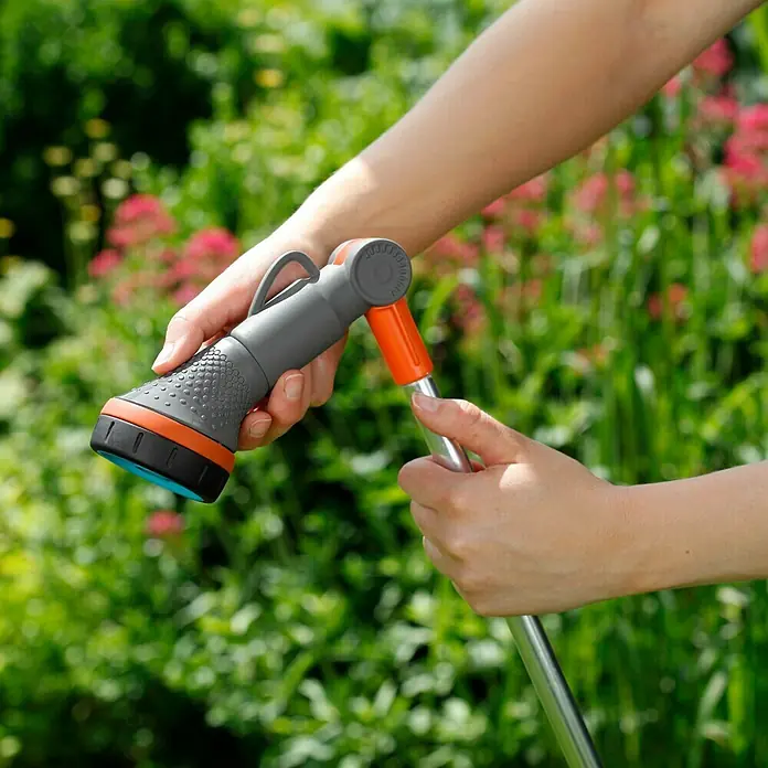 Gardena Comfort Gießstab - 90 cm, Metall/Kunststoff - Eine Person hält einen Gardena-Schlauchspritzenaufsatz mit verschiedenen Sprühmodi, ideal für Gartenbewässerung.