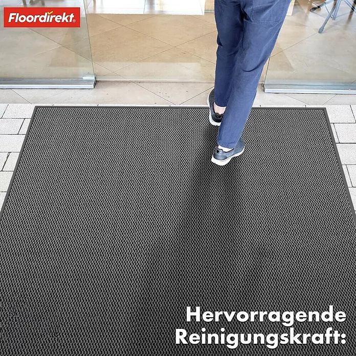 Fußmatte Sky Novo - Anthrazit, 120 x 80 cm, Material Nutzschicht: 100 % Polypropylen - Graue Schmutzfangmatte von Floordirekt vor einer Glastür, eine Person betritt sie. Effektive Reinigungskraft und OEKO-TEX zertifiziert.