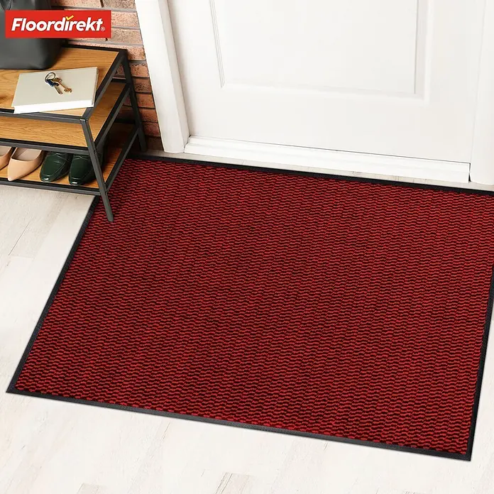 Fußmatte Sky Novo - Rot, 120 x 80 cm, Material Nutzschicht: 100 % Polypropylen - Die Fußmatte in Rot und Schwarz mit dem OEKO-TEX Siegel liegt vor einer weißen Tür und einem Regal.