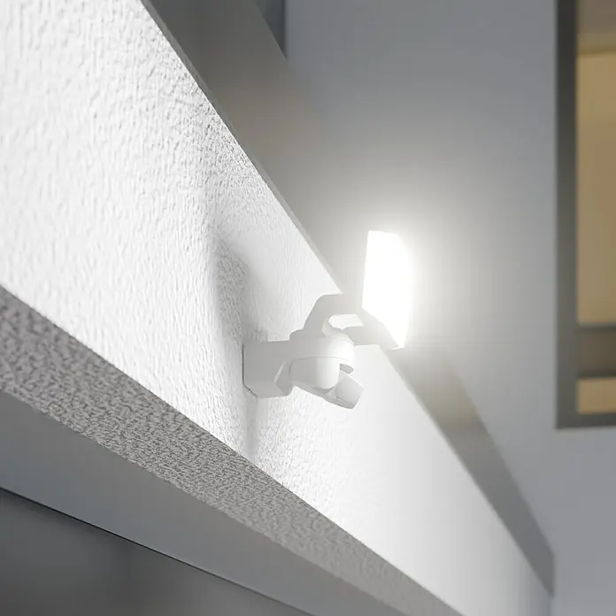 Steinel LED-Sensor-Außenwandleuchte XLED Protect S - 14,3 W, Weiß, Warmweiß - Nahaufnahme einer weißen, an der Wand montierten LED-Sicherheitsleuchte, die hell leuchtet und den Bereich beleuchtet.