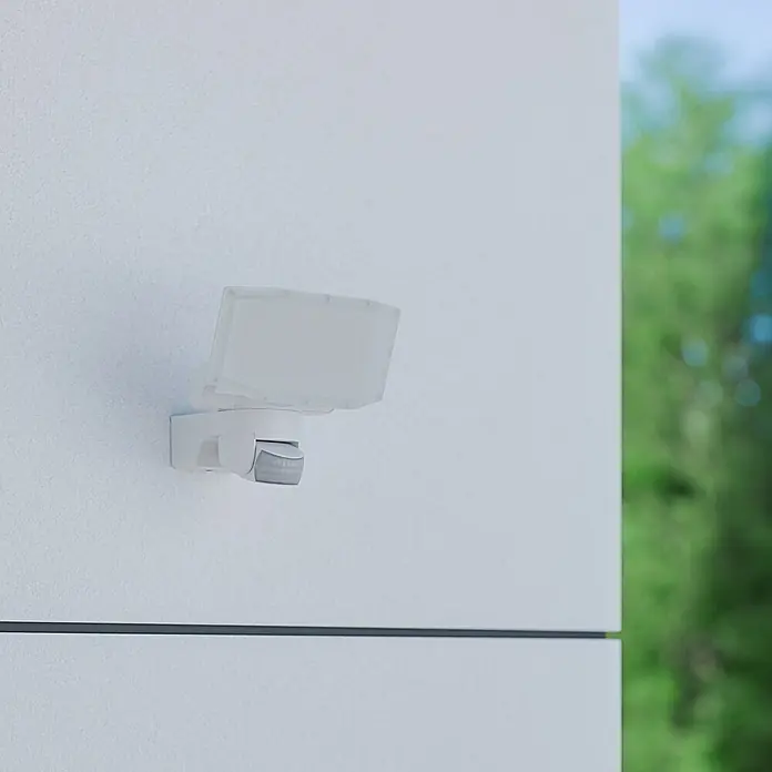 Steinel LED-Sensor-Außenwandleuchte XLED Protect S - 14,3 W, Weiß, Warmweiß - Nahaufnahme einer weißen Außenleuchte mit Bewegungsmelder an einer Fassade.
