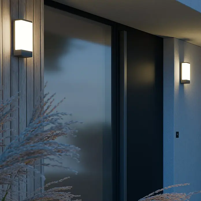 Steinel Außenwandleuchte L 14 - 9,5 x 7 x 27 cm, Anthrazit, IP44, Ohne Bewegungsmelder - Außenansicht eines Hauses mit beleuchteten, rechteckigen Wandleuchten, die ein warmes Licht abgeben und die moderne Fassade hervorheben.