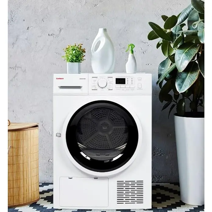 Corberó Secadora CSBCM105 - L x An x Al: 66 x 59,5 x 84,5 cm, Carga soportada: 10 kg - Secadora de ropa blanca con puerta negra y pantalla digital, rodeada de plantas de interior y detergente.