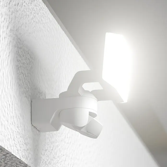 Steinel LED-Sensor-Außenwandleuchte XLED Protect S - 14,3 W, Weiß, Warmweiß - Eine weiße, moderne Außenleuchte mit Bewegungsmelder an einer strukturierten Wand. Das Licht strahlt hell und sorgt für Sicherheit.