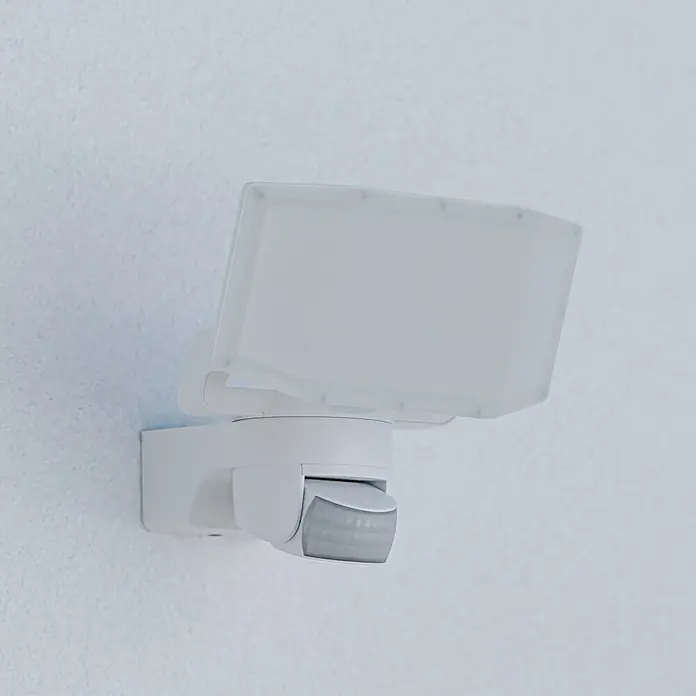 Steinel LED-Sensor-Außenwandleuchte XLED Protect S - 14,3 W, Weiß, Warmweiß - Nahaufnahme einer weißen LED-Außenleuchte mit Bewegungsmelder an einer weißen Wand.