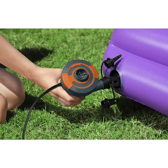 Elektropumpe - 12 V, Max. Fördermenge: 680 l/min - Eine Person benutzt eine Luftpumpe, um eine violette Luftmatratze auf einer grünen Rasenfläche aufzupumpen.