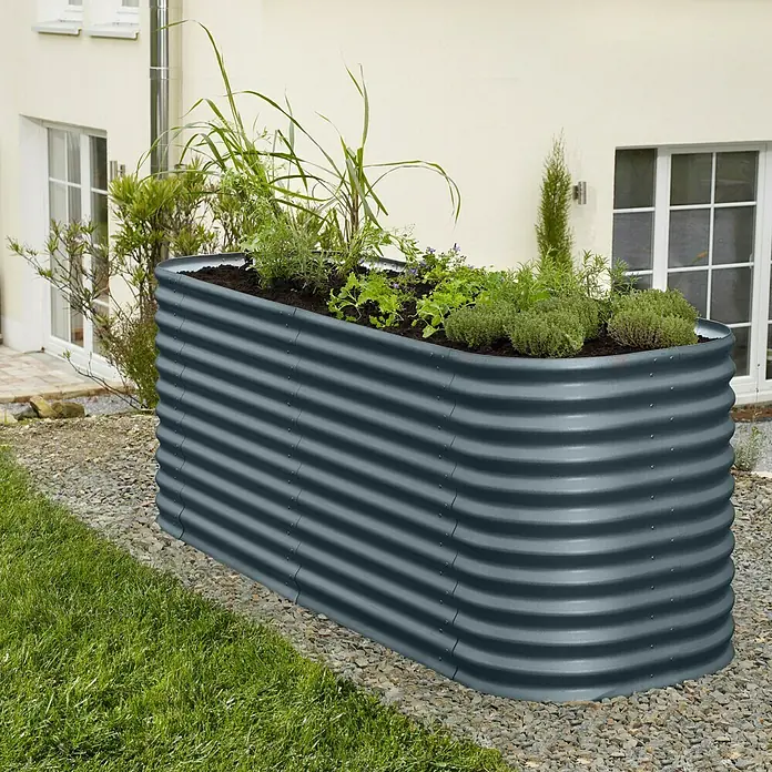 Vitavia Hochbeet-Erweiterung Stretched 858 - 80 x 86 cm, Stahl, Farbe: Granit - Ein Hochbeet aus grauem Metall, bepflanzt mit verschiedenen Kräutern und Pflanzen, steht im Garten vor einem Haus.