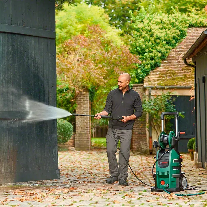 Bosch Hochdruckreiniger AdvancedAquatak 150 - 2.200 W - Der Bosch Hochdruckreiniger reinigt eine Holztür im Freien und entfernt Schmutz mit einem starken Wasserstrahl.