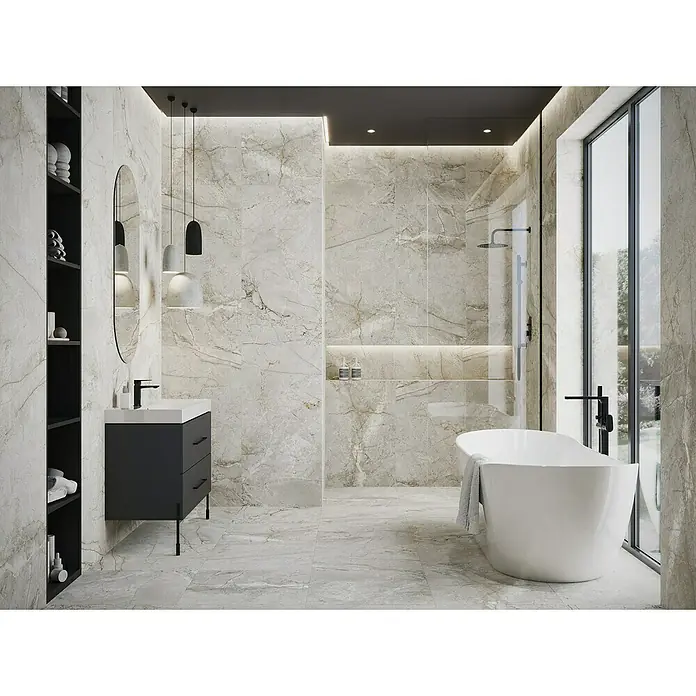 Feinsteinzeugfliese Sinkler - 59,8 x 119,8 cm, Light Grey, Matt - Elegantes Badezimmer mit freistehender Badewanne und dunklem Waschtisch, beleuchtet mit modernen Hängeleuchten. Die Marmorfliesen verleihen dem Raum eine luxuriöse Note.