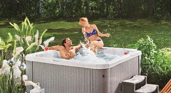 Frau und Mann baden im Außenwhirlpool, dahinter der Garten