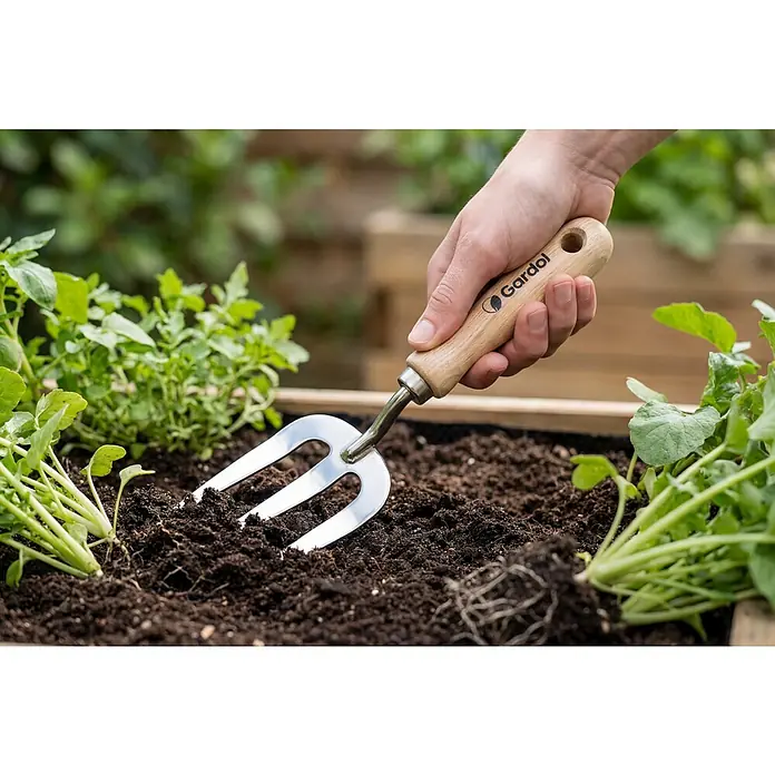Gardol Spatengabel - Anzahl Zinken: 3 Stk. - Gardol Gartenwerkzeug wird in der Erde verwendet, um Pflanzen herum zu lockern. Die Hand hält das Werkzeug.