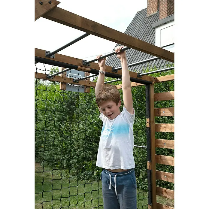 Soulet Kinderspielturm Olympic Odin - L x B x H: 216 x 153 x 209 cm - Ein Junge hängt an einer Reckstange eines hölzernen Klettergerüsts im Garten und lächelt dabei.