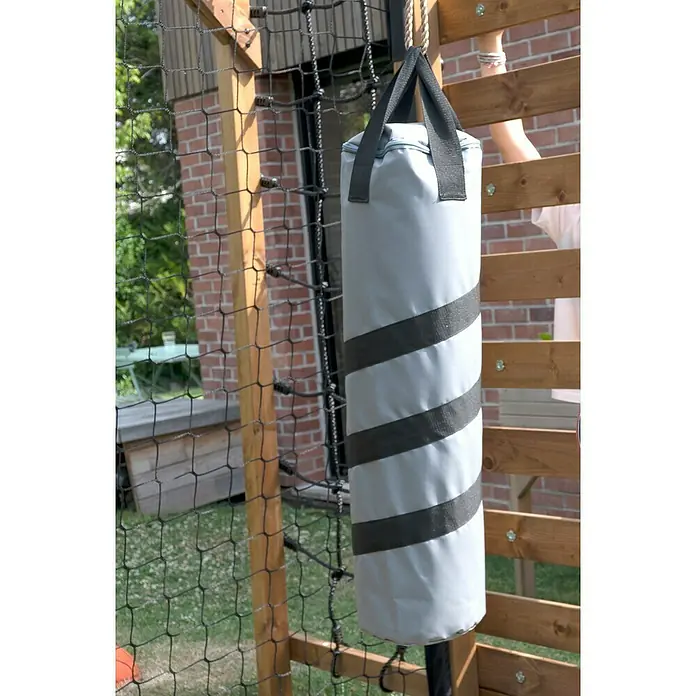 Soulet Kinderspielturm Olympic Odin - L x B x H: 216 x 153 x 209 cm - Nahaufnahme eines Boxsacks mit grauen Streifen, der an einem Seil vor einem Spielplatznetz hängt. Ideal für junge angehende Boxer.