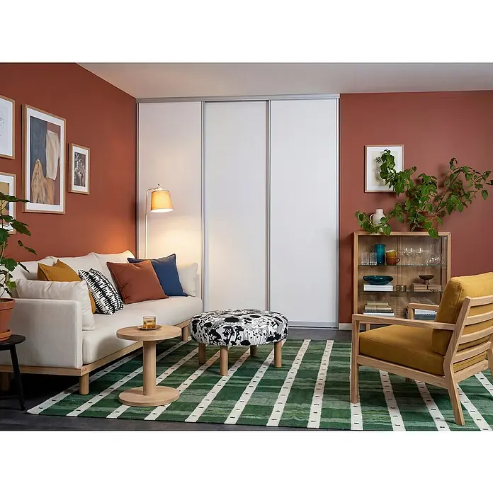 Room Plaza Easy Doing Schiebetür-Bau-Set - Reinweiß Miniperl, Farbe Beschlag: Silber - Geräumiges Wohnzimmer mit bequemen Möbeln und einem grossen, weissen Kleiderschrank mit Schiebetüren, der viel Stauraum bietet.