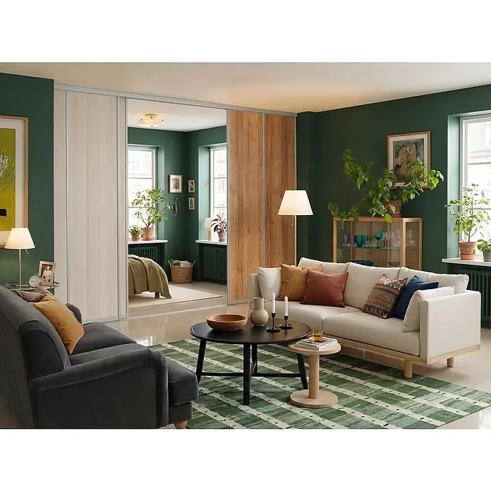 Room Plaza Easy Schiebetür-Bau-Set - Eiche Country/Pinie White, Farbe Beschlag: Silber - Einladendes Wohnzimmer mit einem weißen Sofa, einem grauen Sessel und einem grünen Teppich. Blick durch Schiebetüren in ein Schlafzimmer.