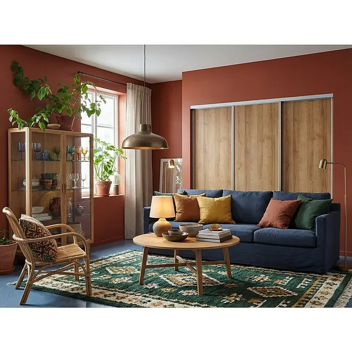 Room Plaza Easy Schiebetür-Bau-Set - Eiche Country/Pinie White, Farbe Beschlag: Silber - Wohnzimmer mit marineblauem Sofa, Couchtisch, Teppich mit Ethnomuster und Vitrine. Die Wände sind in einem warmen Terrakotta-Ton gehalten.