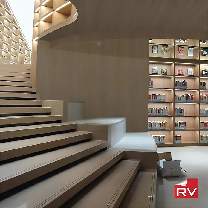 Lámina decorativa autoadhesiva vinílico autoadhesivo a metros - Madera roble - Foto interior de una biblioteca moderna con escaleras y estanterías, creando un ambiente abierto y luminoso.
