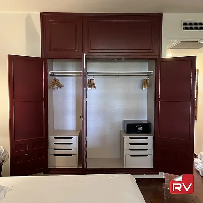 Lámina decorativa autoadhesiva vinílico autoadhesivo a metros - Textil beige claro - Amplio armario con puertas abiertas que muestra perchas, cajones y una caja fuerte.