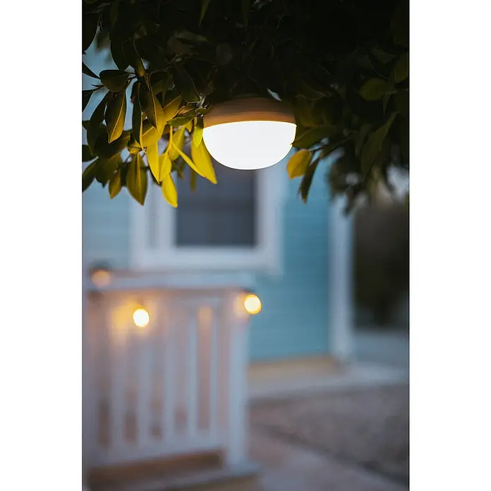 New Garden Akku-Pendelleuchte Cherry - 9 W, L x B x H: 11 x 11 x 8,5 cm, Beige, IP44 - Nahaufnahme einer Solarleuchte im Außenbereich, die an einem Baum befestigt ist und ein warmes Licht abgibt.