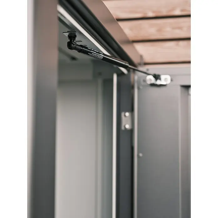 Biohort Romeo Geräteschrank - Außenmaß inkl. Dachüberstand (B x T): 132 x 57 cm, Stahl, Silber-Metallic - Detailansicht eines grauen Schranks mit einem Gasdruckdämpfer, der die Türöffnung unterstützt und für sanftes Schließen sorgt.
