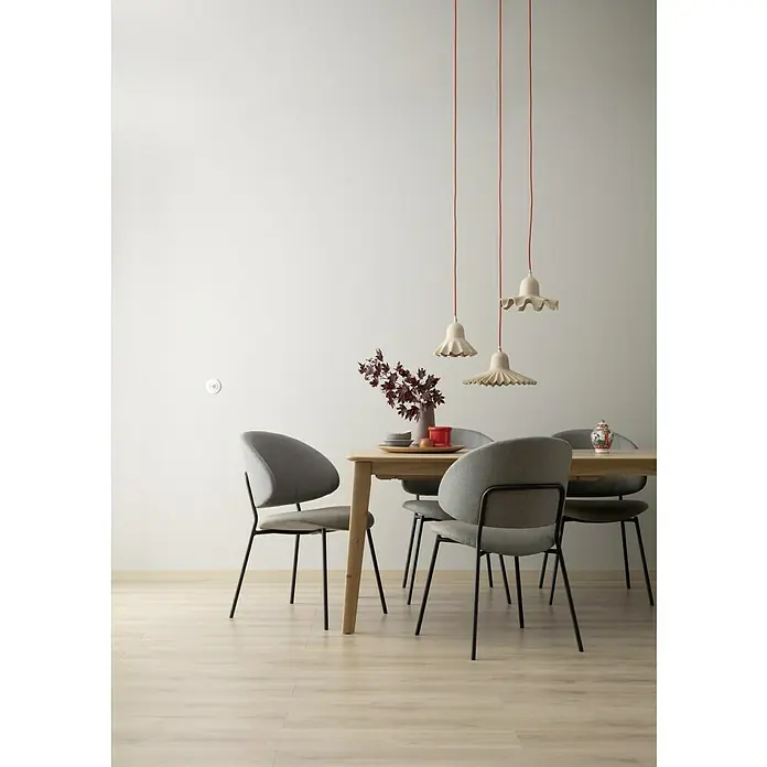 SCHÖNER WOHNEN-Farbe Wandfarbe Designfarbe - Ästhetisches Betongrau, Matt, 2,5 l, Konservierungsmittelfrei - Esszimmer mit Holztisch, grauen Stühlen und drei hängenden Lampen mit rotem Kabel. Das Dekor ist schlicht und modern.