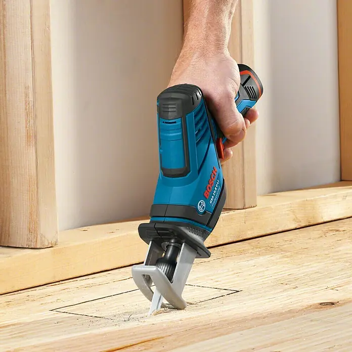 Bosch Professional Akku-Säbelsäge GSA 12V-14 L-Boxx - 12 V, Ohne Akku, Leerlaufhubzahl: 0 /min - 3.000 /min - Nahaufnahme einer Bosch GSA 10,8 V-LI Akku-Säbelsäge beim Sägen eines Holzstücks. Das Werkzeug liegt gut in der Hand und wird präzise geführt.