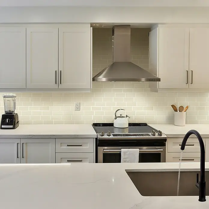 Smart Tiles Selbstklebemosaik Metro - 29,34 x 21,28 cm, Tripoli, Glänzend - Küchenspüle mit Wasserhahn auf einer Kücheninsel, umgeben von Küchengeräten und weißen Schränken. Elegantes Küchendesign mit moderner Funktionalität.