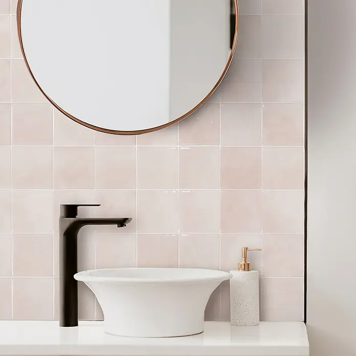 Smart Tiles Selbstklebemosaik Zellige - 22,86 x 22,86 cm, Temera, Glänzend - Ein elegantes Badezimmer-Setup mit einem modernen schwarzen Wasserhahn, einem stilvollen Waschbecken und einem runden Spiegel an der Wand.