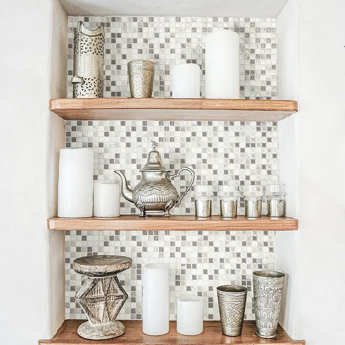 Smart Tiles Selbstklebemosaik Minimo - 29,34 x 24,48 cm, Noche, Glänzend - Regale mit silbernen Teekannen, Gläsern und Kerzen auf einem Mosaikhintergrund für eine elegante und doch gemütliche Atmosphäre.
