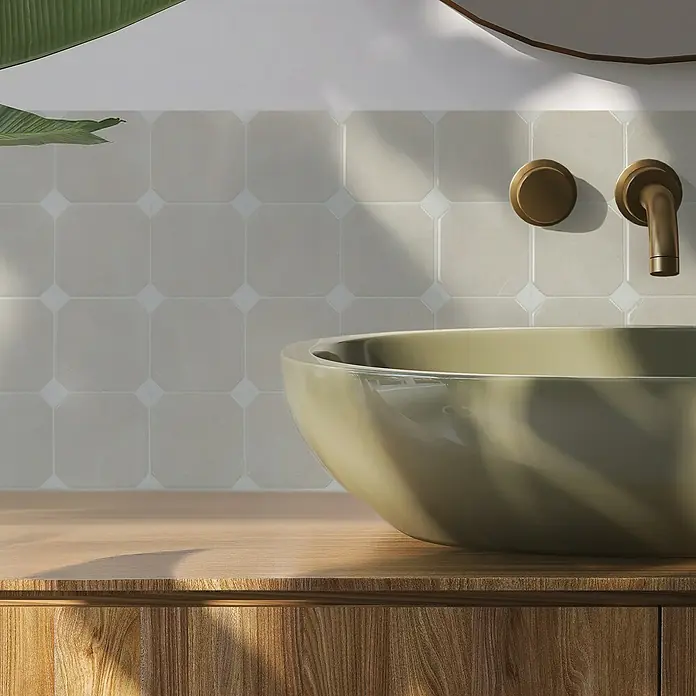 Smart Tiles Selbstklebemosaik Betera - 19,69 x 19,69 cm, Beige, Matt - Nahaufnahme eines modernen Badezimmers mit einem stilvollen, olivgrünen Aufsatzwaschbecken und messingfarbenen Armaturen vor Fliesenspiegel.