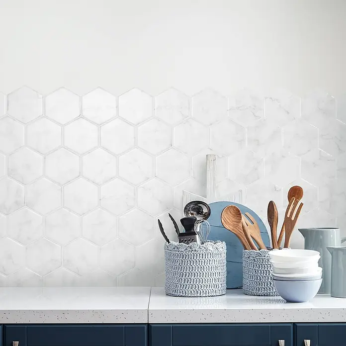 Smart Tiles Selbstklebemosaik Hexa - 24,78 x 23,75 cm, Yule, Glänzend - Dieses Bild zeigt eine Nahaufnahme von Küchenrückwandfliesen in sechseckiger Form. Die Fliesen sind weiß mit einer leichten Marmorierung.