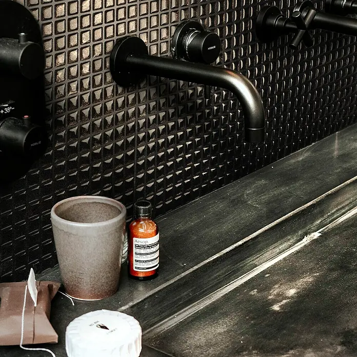 Smart Tiles Selbstklebemosaik Minimo - 29,34 x 24,48 cm, Nero, Glänzend - Detailaufnahme einer stilvollen Badezimmerarmatur mit einer Aesop-Handseife, die das luxuriöse Ambiente unterstreicht.