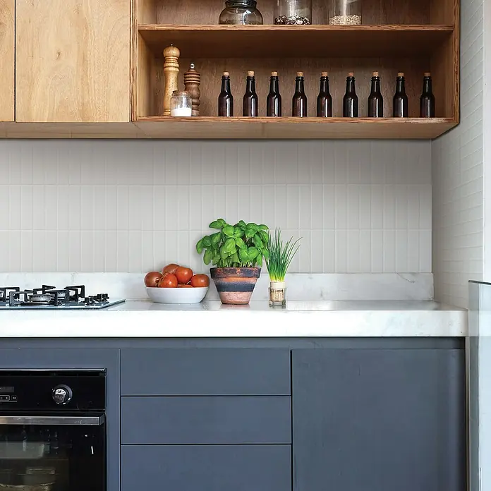 Smart Tiles Selbstklebemosaik Morocco - 29,02 x 22,86 cm, Casablanca, Matt - Küchenszene mit Herd, Arbeitsplatte, Gemüse und Kräutern. Holzregal mit Dekoration sorgt für eine warme Atmosphäre in der Küche.
