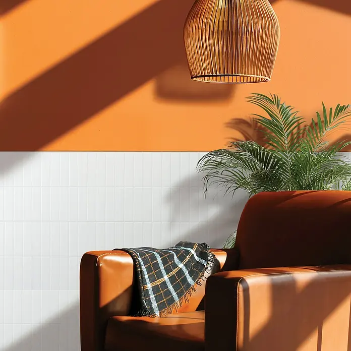 Smart Tiles Selbstklebemosaik Morocco - 29,02 x 22,86 cm, Casablanca, Matt - Dieses stimmungsvolle Interieur zeigt eine stilvolle Lampe über einem Ledersessel mit einer karierten Decke, ergänzt durch eine Zimmerpflanze.